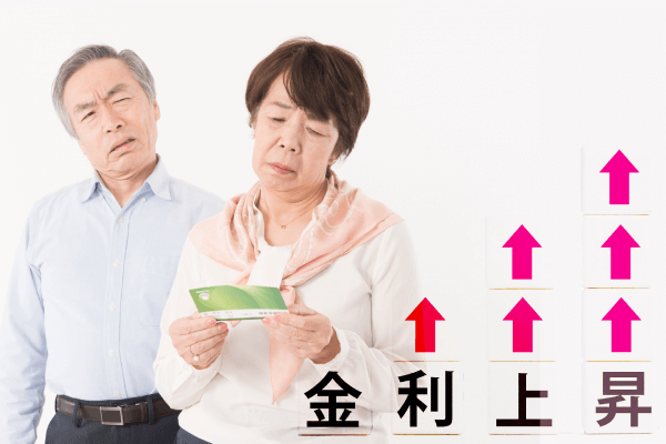 通帳を見て肩を落とす高齢夫婦と上昇する金利グラフ